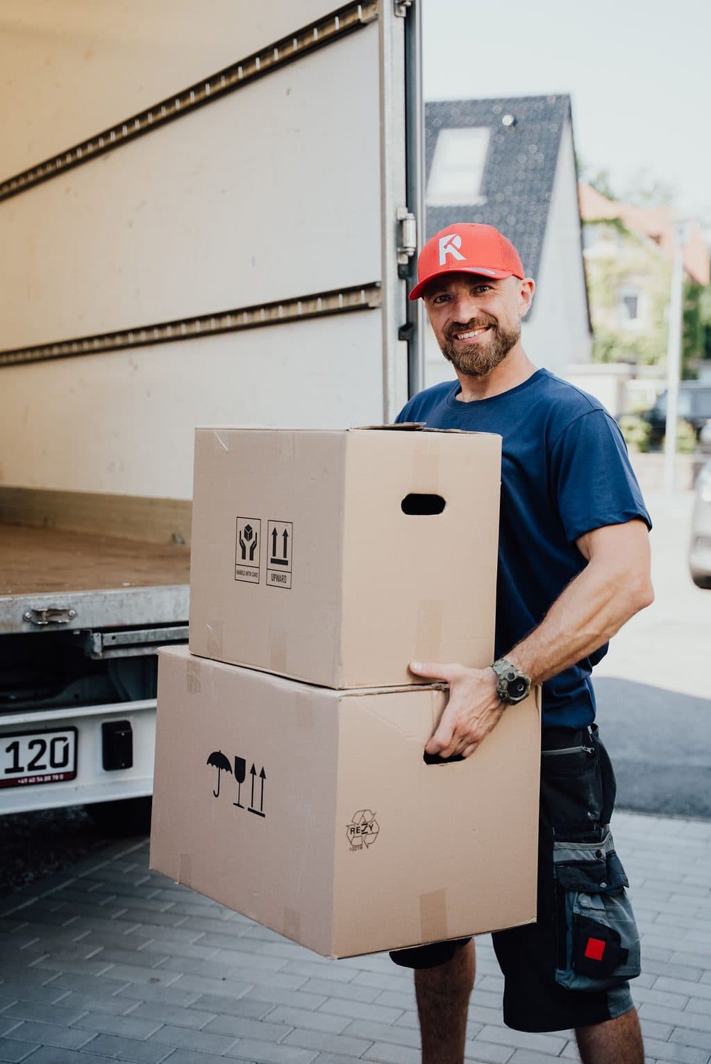 Mitarbeiter trägt Kartons aus dem Transporter